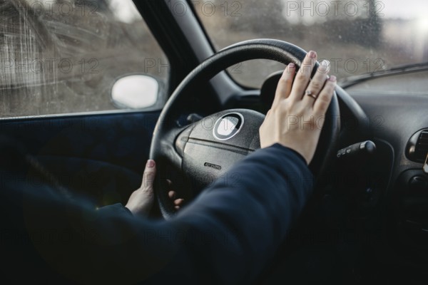 Person places hand on wheel as if to use the horn inside an overcast vehicle