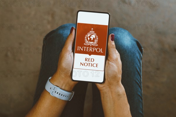 In this photo illustration, the Interpol Red Notice logo is displayed on a smartphone screen
