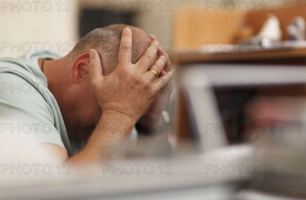 Worried businessman sitting in front of his computer with his head in his hands