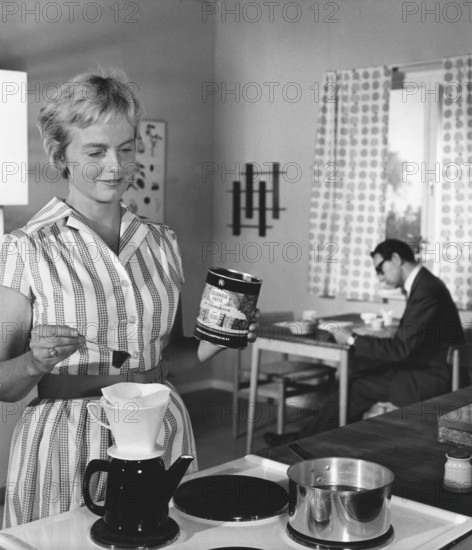 Coffee in the 1960s. A woman is making coffee for her herself and her husband. The way of making coffee at this time was usually to pour hot water through a filter holder into a coffee pot. There were electric coffee makers already in the 19th century, but the modern electric maker as we know it today was only launched in the 1950s. Melitta launched the first coffee maker MA 120 in the 1960s. At this time, an electric maker was a real luxury item. Today, the electric coffee maker is more of a standard product, which can be found in almost every home and there is a whole host of coffee makers in different price ranges. Sweden 1960