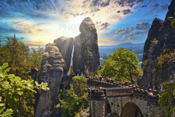 Stone Bastei Bridge connects imposing rocks at sunset, surrounded by lush trees, Elbe Sandstone Mountains, Saxon Switzerland, Saxony, Germany, Europe