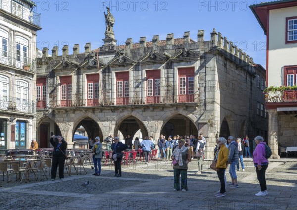 Tourist group viewing historic buildings in Largo da Oliveira square, city of Guimaraes, northern Portugal