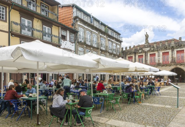 Tables and chairs, historic buildings in Largo da Oliveira square, city of Guimaraes, northern Portugal