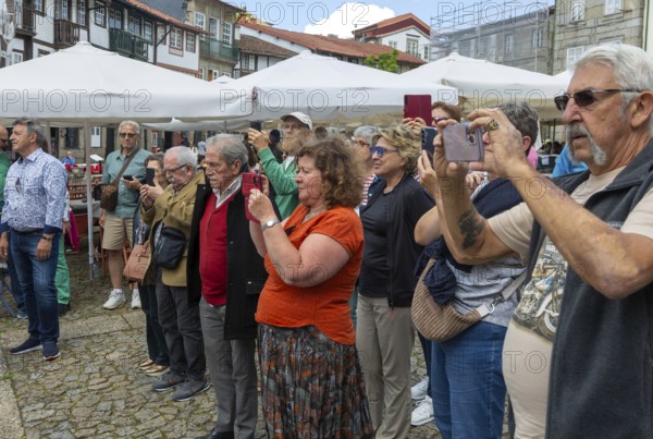 People taking photos with their phones, Praça de São Tiago, city of Guimaraes, northern Portugal