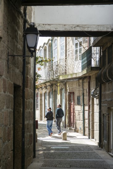 Coupe walking exploring alleyways in historic centre of ity of Guimaraes, northern Portugal