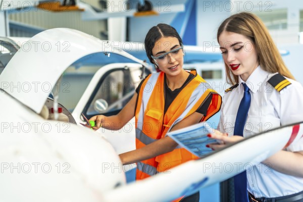 Aircraft maintenance engineer and a pilot are performing a pre flight check, consulting a maintenance log, ensuring the aircraft's safety and airworthiness