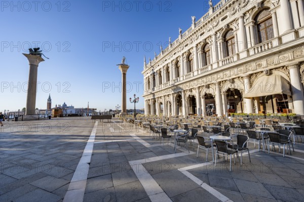 Chairs and tables of cafes at Piazetta San Marco, Colonna di San Marco and Colonna di San Todaro, in the morning light, St Mark's Square, Venice, Veneto, Italy, Europe