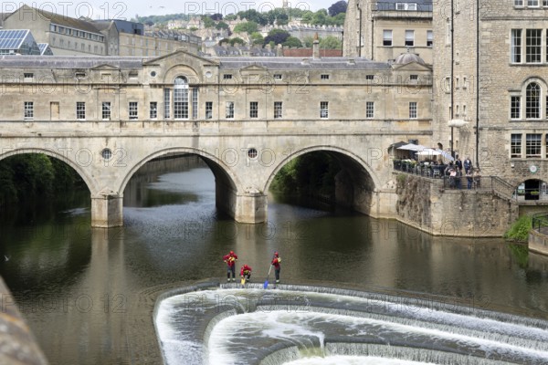 Avon Fire and Rescue Service personnel on weir on River Avon, Pulteney Bridge, city of Bath, north east Somerset, England, UK