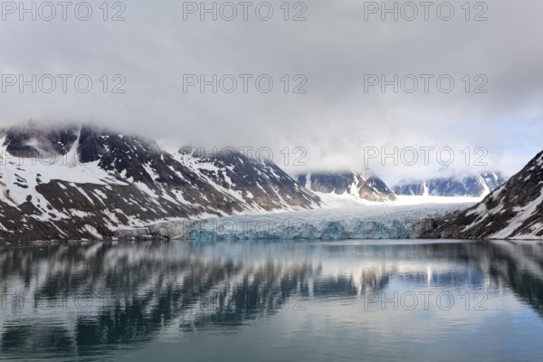 An impressive lake reflects the surrounding glaciers and mountains, surrounded by clouds and a calm atmosphere, Magdalenenfjord with Waggonway Glacier, Svalbard, Norway, Europe