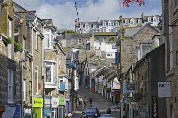 A busy town street with traditional stone houses and many passers-by, holiday resort, St Ives, Cornwall, England, United Kingdom, Europe