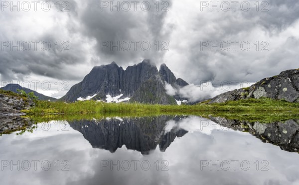Small lake in mountain landscape, hike to Mount Barden, reflection with mountain peak Breidtind, Senja, Norway, Europe
