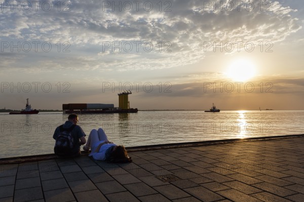 Tourists enjoying the view, sunset on the Weser, pier Seebäderkaje, pontoon, Willy-Brandt-Platz, Havenwelten, Bremerhaven, Bremen, Germany, Europe