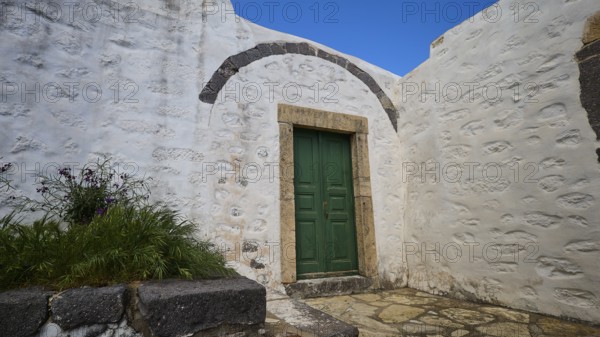 Green door in a courtyard with plants and whitewashed walls, Monastery of the Revelation, Moni tis Apokalipsis, World Heritage Site 1999, Patmos, Dodecanese, Greek Islands, Greece, Europe