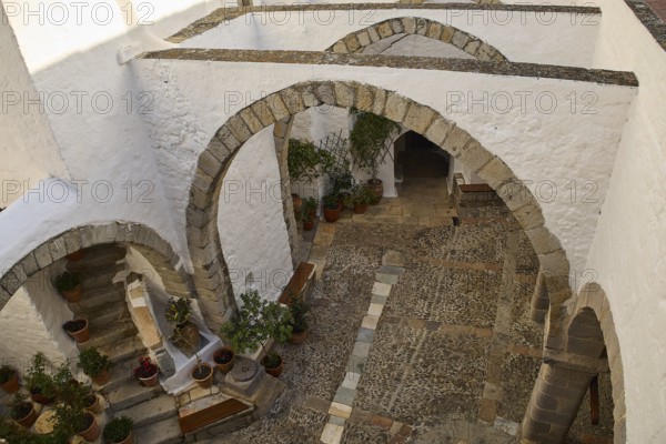 White courtyard with stone arches and plants in traditional style, Monastery of St John the Theologian, Monastery of St John the Theologian, World Heritage Site 1999, Patmos, Dodecanese, Greek Islands, Greece, Europe