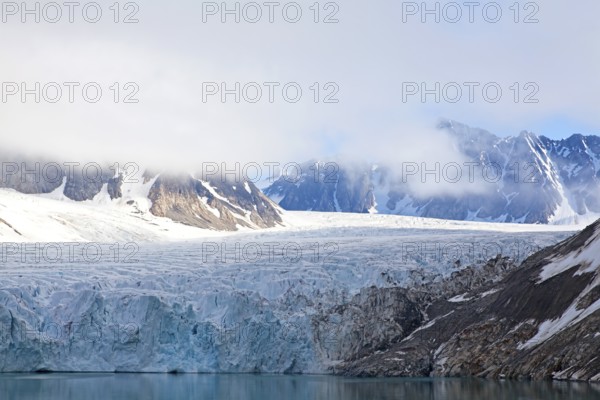 A fascinating glacier with snow-covered mountains and clouds creating a calm and peaceful atmosphere, Magdalenenfjord with Waggonway Glacier, Svalbard, Norway, Europe