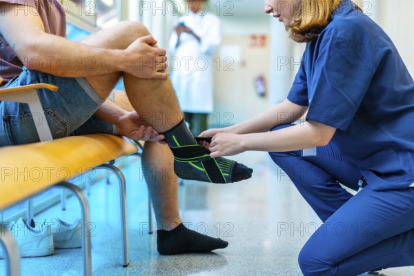 Female nurse bandaging a male patient's injured ankle in a hospital setting, providing support and care