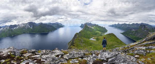 Panorama, view of fjords Øyfjorden and Mefjorden, mountains on the headland of Fjordgård, view from the mountain Barden, young man looking into the distance, Senja, Norway, Europe