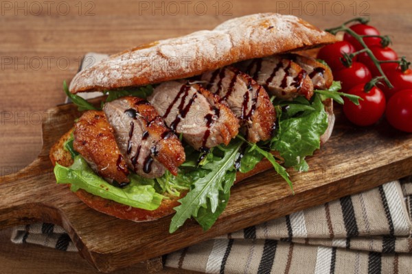 Sandwich with duck breast and arugula, balsamic sauce, on a wooden chopping board, breakfast, homemade, without people