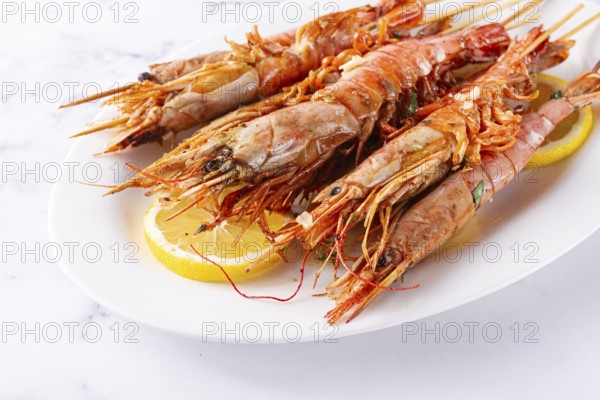 Freshly grilled prawns served, on a white platter, with lemon slices, for a delicious seafood experience