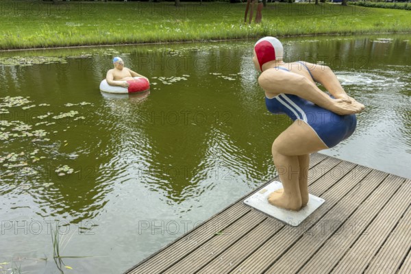 Publicly exhibited artistic sculptures by Christel and Laura Lechner in the frog pond on the town wall of Rees on the Lower Rhine Everyday people left figure Paul swimming tyre man man with swimming tyre, right female figure jumper woman in swimming costume with swimming cap, Rees, North Rhine-Westphalia, Germany, Europe