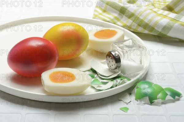 Easter eggs and salt shaker on plate, partially peeled
