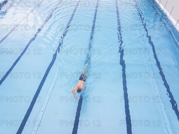 A person swims along the lanes in a large, blue swimming pool, outdoor pool Calw, Black Forest, Germany, Europe