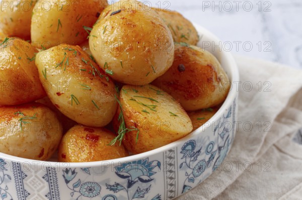 Baked new potatoes, with butter and dill, on a white plate, at home, no people