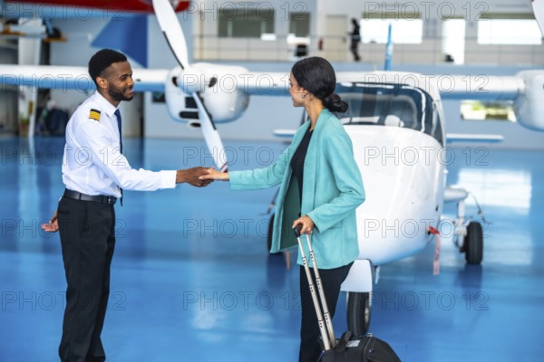 Pilot and businesswoman shaking hands in front of a private jet inside a hangar, finalizing their partnership before departure