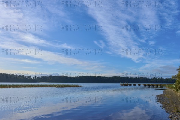 A long jetty on the shore of a calm lake under an overcast sky, Lake Mahinapua, Ruatapu, South Island, New Zealand, Oceania