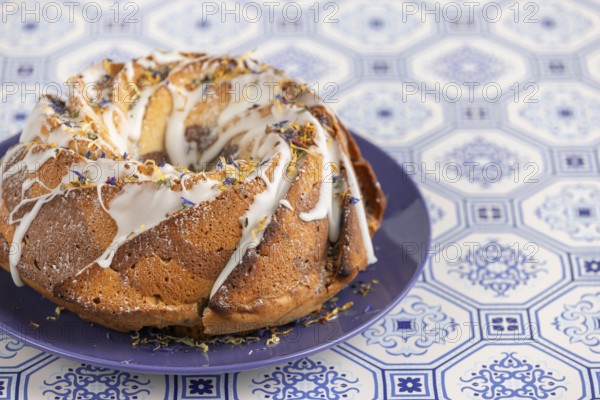 Marble bundt cake, cake with icing and edible flowers on a blue plate