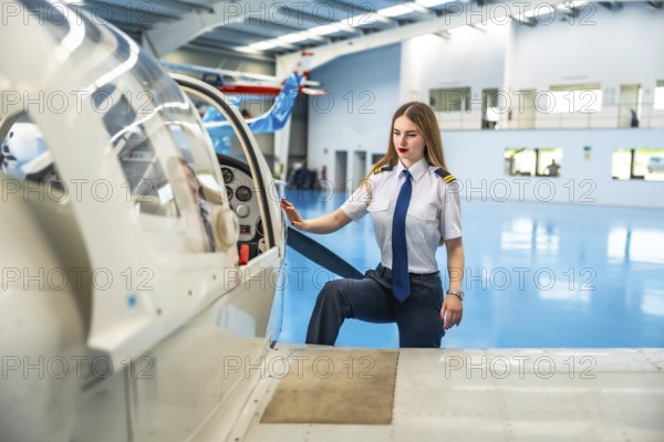 Confident female pilot boarding a small aircraft in a hangar, readying for an exciting flight and embracing the adventure ahead