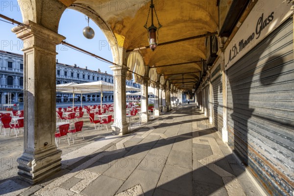 Chairs and tables of cafes, arcades at St Mark's Square in the morning light, Venice, Veneto, Italy, Europe