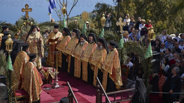 Priests in golden robes lead a religious ceremony on a decorated stage in front of a Greek flag and spectators, Orthodox ceremony, monks of St John's Monastery, ceremonial washing of feet, procession, Maundy Thursday, Megali Pempti, Chora, Patmos, Dodecanese, Greek Islands, Greece, Europe