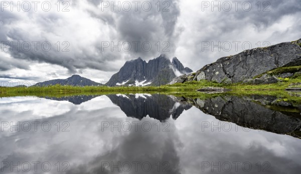Small lake in mountain landscape, hike to Mount Barden, reflection with mountain peak Breidtind, Senja, Norway, Europe