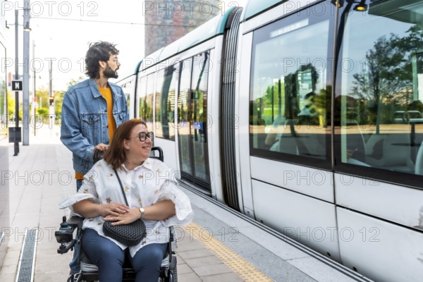 Caregiver pushing a smiling woman in a wheelchair at a modern tram station, both eagerly waiting to board the accessible transport