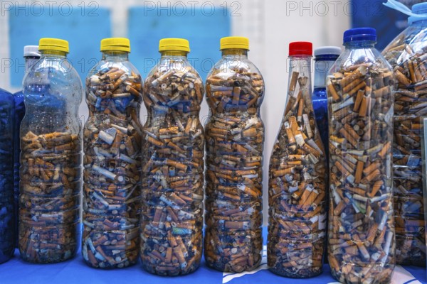 Plastic bottles filled with cigarette butts collected during a beach cleanup highlight environmental pollution and human impact