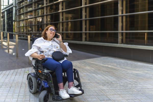 Happy businesswoman using a smartphone in a wheelchair, enjoying a moment of connectivity in the urban environment