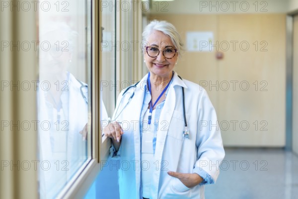 Portrait of a confident senior female doctor standing in a bright hospital corridor, representing healthcare expertise and professionalism