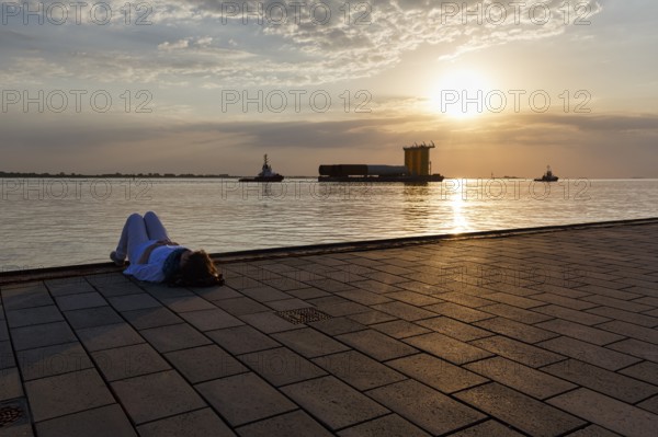 Tourist enjoying the view, sunset on the Weser, pier Seebäderkaje, pontoon, Willy-Brandt-Platz, Havenwelten, Bremerhaven, Bremen, Germany, Europe