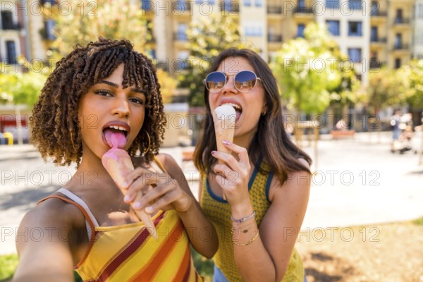 Two happy female friends are enjoying a refreshing ice cream cone on a sunny day in a city park