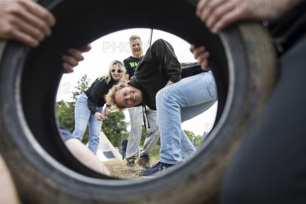 Festival visitors look through a car tyre on a campsite at the Rock am Ring Festival on Saturday, Nürburgring race track race track, 07.06.2025