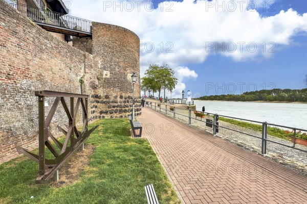 View of historic town wall and former customs tower for customs duties on the Rhine promenade of Rees on the Lower Rhine, old anchors on the left in the foreground, Rhine river on the right, Rees, North Rhine-Westphalia, Germany, Europe