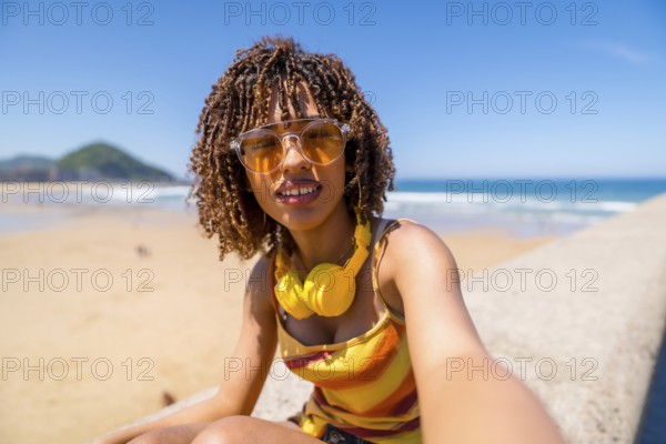 Tourist enjoying summer holidays at the beach, capturing a joyful selfie while soaking up the sun, surrounded by ocean waves and sandy shores