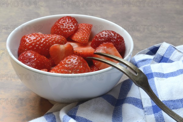 Sliced strawberries in hull with fork, Fragaria