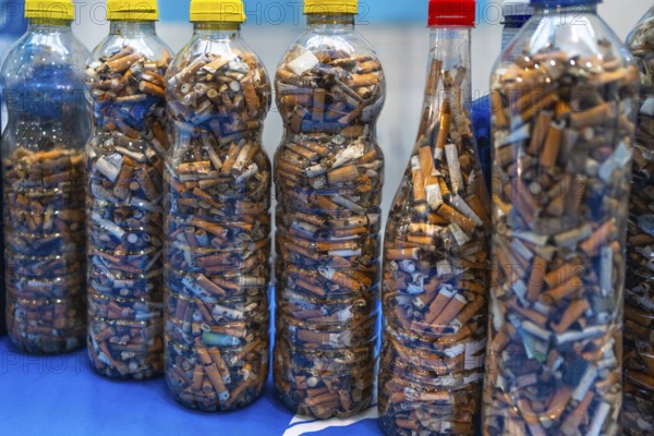 Plastic bottles filled with used cigarette butts highlight the environmental impact of smoking and improper disposal, raising awareness about pollution