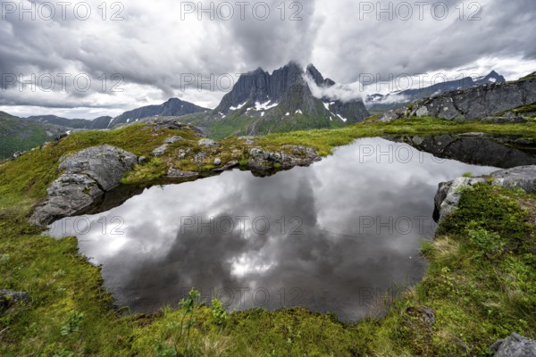 Small lake in mountain landscape, hike to Mount Barden, reflection with mountain peak Breidtind, Senja, Norway, Europe