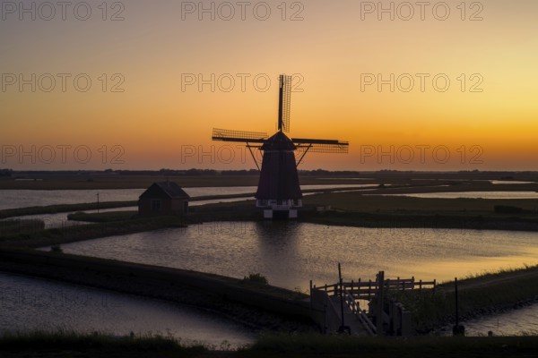 1878 windmill Het Noorden, traditional polder mill, smock mill near Oosterend on the island Texel at sunset, North Holland, the Netherlands