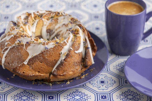 Marble bundt cake, cake with icing and edible flowers on a blue plate with coffee