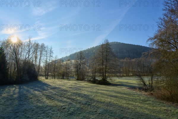The sky illuminates a meadow and trees in front of a wooded hill, Kirchzell, Amorbach, Odenwald, Bavaria, Germany, Europe