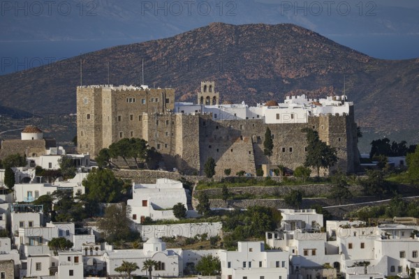 Stone castle towers over a village with white houses and surrounding mountains, Monastery of St John the Theologian, Monastery of St John the Theologian, World Heritage Site 1999, Chora, Patmos, Dodecanese, Greek Islands, Greece, Europe